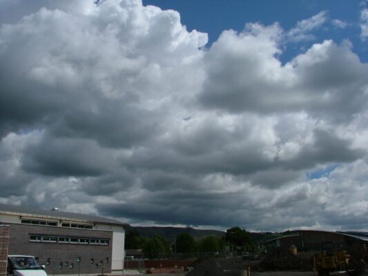 Dramatic clouds over the nearly finished building, with the Ochil Hills on the horizon.
