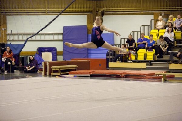 Gymnast mid-air in a leap across the floor at the 2012 club display