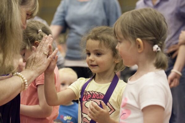 Two young children giving a high five during a pre-school gymnastics session