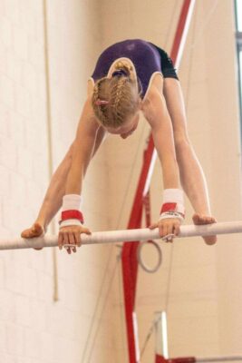 Young gymnast folding over the high bar