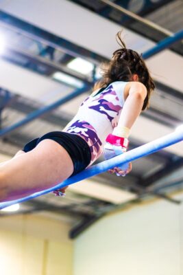 Gymnast swinging beneath the bar, photographed from below