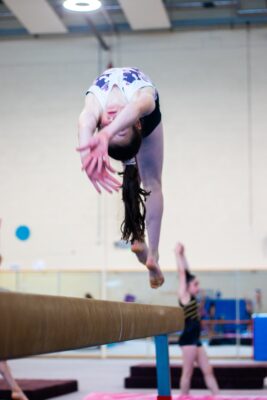 Gymnast mid back handspring above the beam