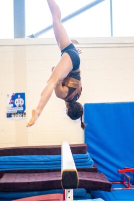 Gymnast in a vertical handstand on the beam