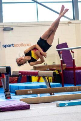 Gymnast somersaulting over the low beam