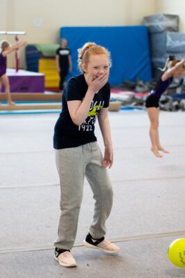 Young gymnast smiling for the camera between turns