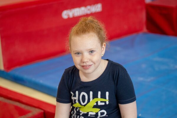 Young gymnast smiling for the camera between turns