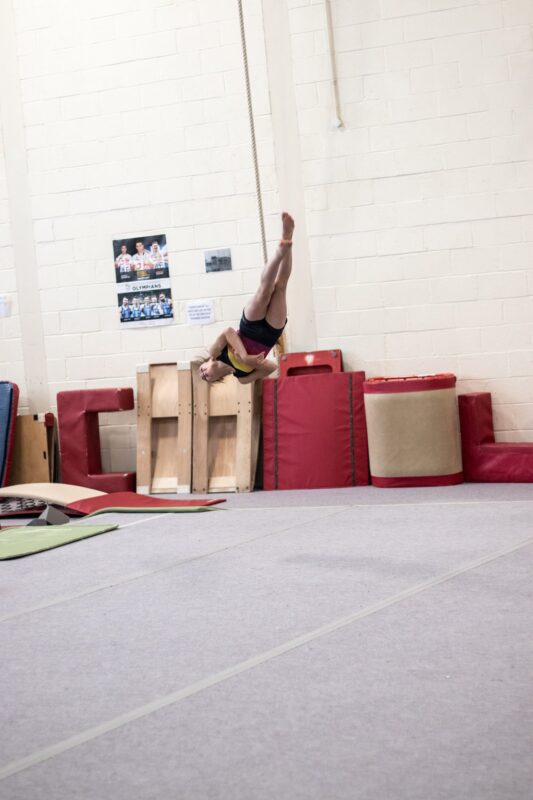 Gymnast holding a handstand across the gym floor