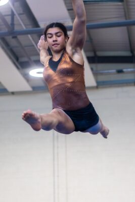 Gymnast performing a split leap high above the floor in front of the audience at the 2012 club display