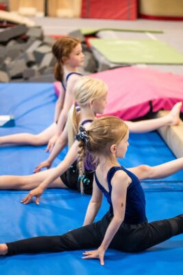 Young gymnasts practising splits on the mats